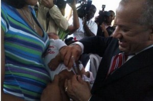 Ministro de Salud, Freddy Hidalgo, mientras vacuna bebé contra Neumococo en el Hospital Robert Reid Cabral. 