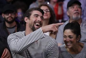 En esta foto de archivo del 21 de marzo de 2017, el nadador Michael Phelps, izquierda, y su esposa Nicole Johnson ríen durante un partido de la NBA entre los Lakers y Clippers, en Los Angeles. (AP Photo/Jae C. Hong, File)