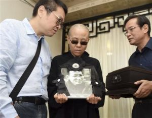 En esta imagen, proporcionada por la Oficina de Información Municipal de Shenyang, Liu Xia (centro), la esposa del fallecido disidente y Premio Nobel de la Paz Liu Xiaobo, sostiene un retrato suyo durante su funeral, en una funeraria en Shenyang, en el noreste de la provincia china de Liaoning, el 15 de julio de 2017. En la imagen aparecen, de izquierda a derecha, Liu Hui, hermano menor de Liu Xia; Liu Xia y Liu Xiaoxuan, hermano pequeño de Liu Xiaobo, quien sostiene las cenizas del fallecido. (Oficina de Información Municipal de Shenyang via AP)
