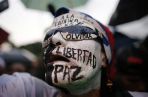 Una mujer con el rostro pintado participa en una vigilia para rendir homenaje a las más de 90 personas que han muerto durante tres meses de protestas contra el gobierno venezolano, en Caracas, Venezuela, el jueves 13 de julio de 2017. (AP Foto/Ariana Cubillos)