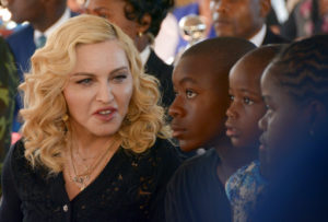 FILE- In this July 11, 2017 file photo, Madonna, left, sits with her adopted children David, Stella and Mercy, at the opening of The Mercy James Institute for Pediatric Surgery and Intensive Care, located at the Queen Elizabeth Central Hospital in the city of Blantyre, Malawi. A lawyer for Madonna said Thursday July 27, 2017, that the star and her twin daughters Stella and Estere have accepted damages form the publisher of the Mail Online website over an article that was a 