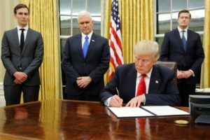 U.S. President Donald Trump, flanked by Senior Advisor Jared Kushner (standing, L-R), Vice President Mike Pence and Staff Secretary Rob Porter welcomes reporters into the Oval Office for him to sign his first executive orders at the White House in Washington, U.S. January 20, 2017. REUTERS/Jonathan Ernst     TPX IMAGES OF THE DAY
