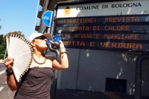 SOL01 BOLONIA (ITALIA), 01/08/2017.- Una mujer bebe agua frente a un cartel que marca las altas temperaturas en Bolonia, Italia, hoy, 1 de agosto de 2017. En el cartel se lee 