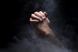 Praying hands over dark background. Christian Pray