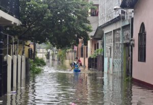 Dos jóvenes hondureños abandonan sus viviendas inundadas debido a las fuertes lluvias hoy en La Lima (Honduras). EFE/Jose Valle
