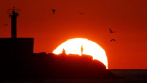 Dos pescadores faenan mientras el sol se pone en la punta del muelle del puerto de la localidad coruñesa de Portosín. EFE/ Lavandeira Jr/Archivo