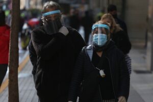 En la imagen, dos ciudadanos protegidos con mascarilla y careta caminan por el principal corredor peatonal del centro de Santiago (Chile). EFE/Elvis González/Archivo