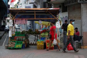 Dos personas caminan frente a un negocio de verduras en la avenida central hoy, en Ciudad de Panamá (Panamá). EFE/Bienvenido Velasco