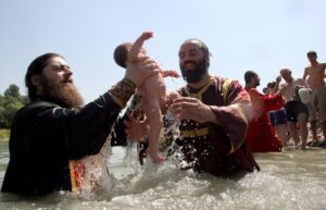 Dos sacerdotes ortodoxos georgianos sostienen un niño durante una ceremonia de Bautismo, en el Río Aragvi, a las afueras de Tbilisi, Georgia. EFE/ZURAB KURTSIKIDZE/Archivo