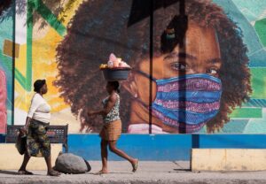 Dos mujeres caminan frente a un mural alusivo al uso del tapabocas por el coronavirus en Puerto Príncipe (Haití). EFE/ Orlando Barría/Archivo