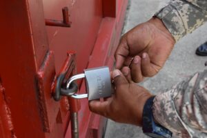 Un agente de la Policía coloca un candado a la puerta de las instalaciones de Kingston Aluminium. La empresa está ubicada en el municipio de Guerra, Provincia Santo Domingo